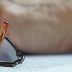 A pair of reading glasses resting on a legal document, with a blurred hand in the background, symbolizing the review of Articles of Association in Thailand.