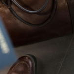 A person holding a passport near a leather travel bag, symbolizing international travel and visa processes, including the application for a long term resident visa.