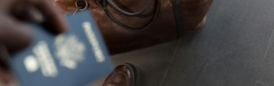 A person holding a passport near a leather travel bag, symbolizing international travel and visa processes, including the application for a long term resident visa.