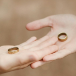 Two individuals in formal attire holding wedding rings in their hands, symbolizing marriage equality law