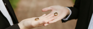 Two individuals in formal attire holding wedding rings in their hands, symbolizing marriage equality law