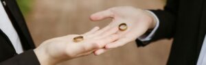 Two individuals in formal attire holding wedding rings in their hands, symbolizing marriage equality law