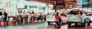 Busy street in Bangkok with cars and motorbikes, highlighting the importance of having a valid driving license in Bangkok.