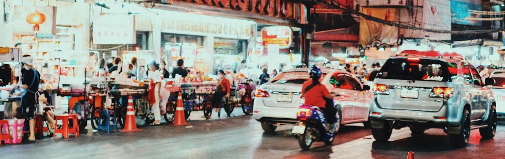 Busy street in Bangkok with cars and motorbikes, highlighting the importance of having a valid driving license in Bangkok.