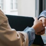 Two professionals shaking hands after reaching an agreement through Thailand Arbitration in a modern office setting.