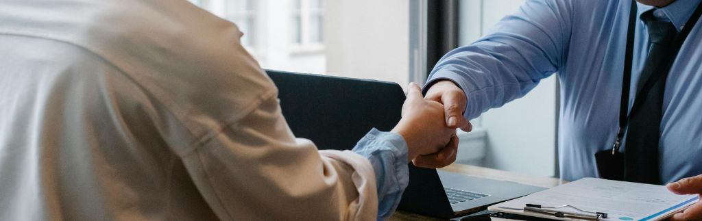 Two professionals shaking hands after reaching an agreement through Thailand Arbitration in a modern office setting.