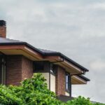 Maison moderne entourée de verdure sous un ciel nuageux, illustrant la stabilité et la résidence en Thaïlande, en lien avec l'obtention d'un certificat de résidence en Thaïlande.