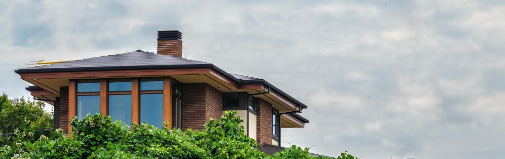 Maison moderne entourée de verdure sous un ciel nuageux, illustrant la stabilité et la résidence en Thaïlande, en lien avec l'obtention d'un certificat de résidence en Thaïlande.