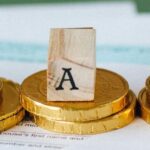 Taxes in Thailand for Expats: wooden blocks spelling 'TAX' on gold coins with tax documents in the background, symbolizing expatriate tax obligations.