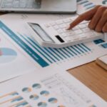 Person reviewing business charts and calculator related to Thailand tax code