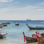 Traditional boats on a beach in Krabi, symbolizing the peaceful lifestyle you can enjoy when you buy house in Krabi