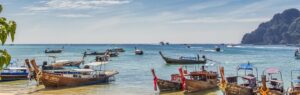 Traditional boats on a beach in Krabi, symbolizing the peaceful lifestyle you can enjoy when you buy house in Krabi