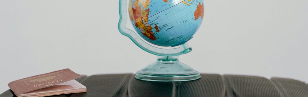 Passport and globe on suitcase representing travel preparations for a visa to live in Thailand