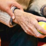 Hands of an elderly person being supported, representing retirement visa renewal Thailand.