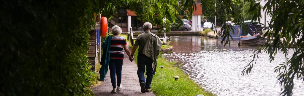 Couple de retraités marchant au bord d’un canal, illustrant le renouvellement du visa retraite Thaïlande dans un cadre paisible.