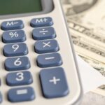 US dollar bills next to a calculator, representing the Thailand visa price analysis