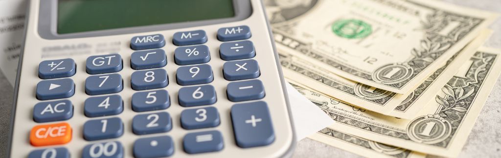 US dollar bills next to a calculator, representing the Thailand visa price analysis