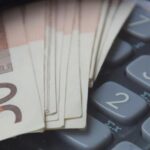 Billets de 50 euros et calculatrice sous loupe, illustrant le prix d'un visa en Thaïlande