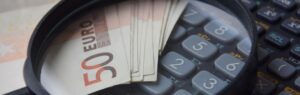 Billets de 50 euros et calculatrice sous loupe, illustrant le prix d'un visa en Thaïlande