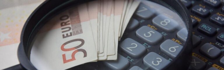 Billets de 50 euros et calculatrice sous loupe, illustrant le prix d'un visa en Thaïlande