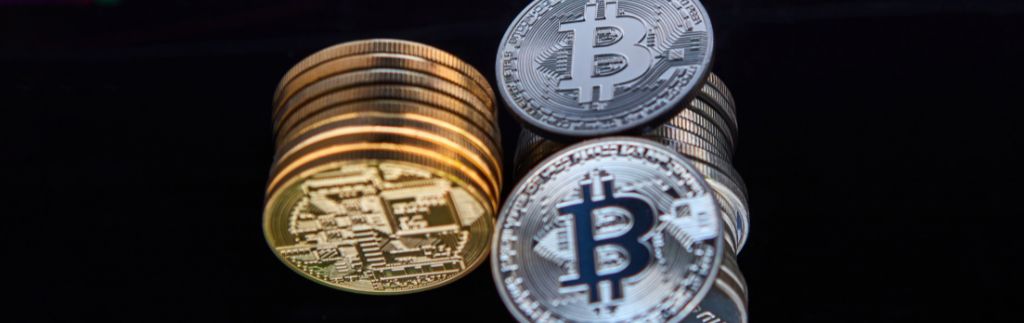 Криптовалюта в Таиланде: стопки золотых и серебряных биткоинов на темном фоне
