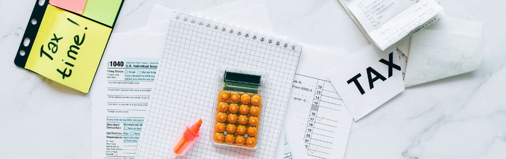 Tax documents, calculator, and highlighter on a flat surface, representing import taxes in Thailand.