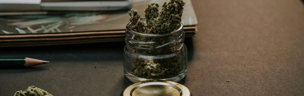 Cannabis buds in a glass jar on a desk – weed law Thailand context