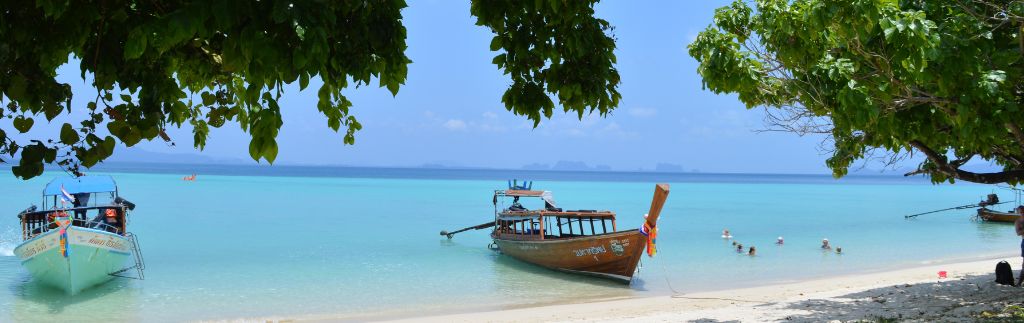 Long-tail boats on a tropical beach, perfect scenery for foreigners living in Krabi.