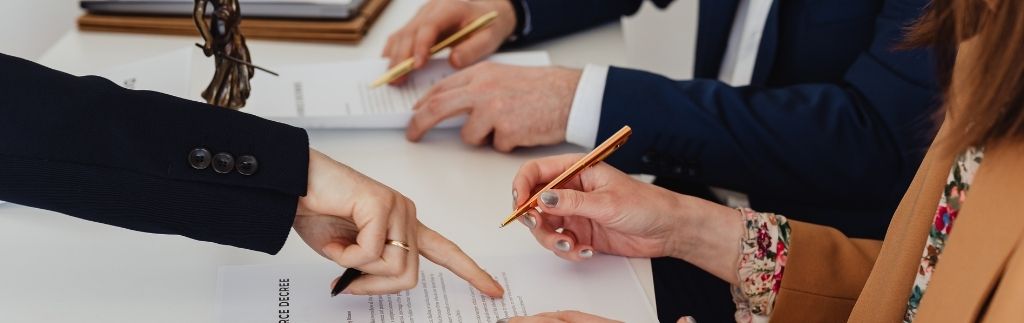Personen unterzeichnen juristische Dokumente im Büro – Symbolbild für Scheidung Thailand.