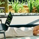 Une femme travaillant sur son ordinateur portable au bord d’une piscine, illustrant la vie d’un digital nomade à Bangkok.