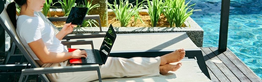 Une femme travaillant sur son ordinateur portable au bord d’une piscine, illustrant la vie d’un digital nomade à Bangkok.