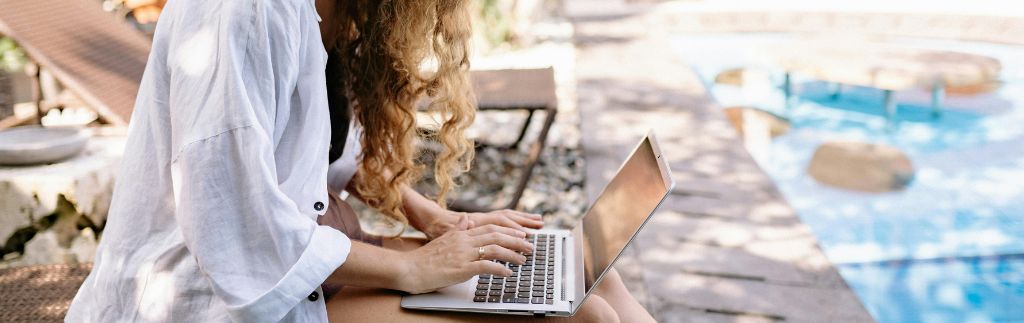 Digital nomad in Thailand working remotely by the pool on a laptop