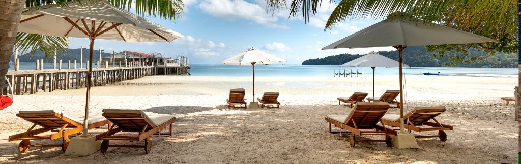 Spiaggia tropicale con lettini e ombrelloni a Phuket, ideale per chi sogna di comprare casa a Phuket e vivere fronte mare.