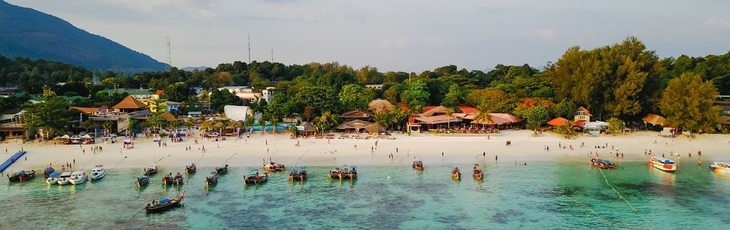 Panorama eines thailändischen Strandes mit Booten und türkisfarbenem Meer – Symbol für den Traum vom Umzug Thailand.
