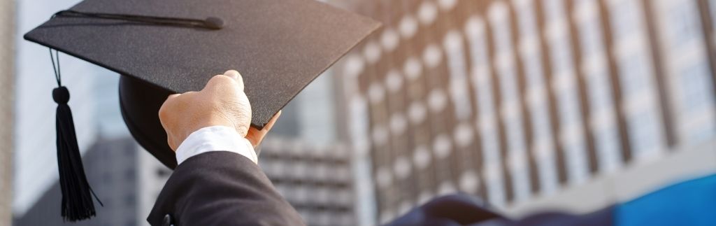 Ein Absolvent hält seinen Doktorhut in die Höhe – Symbol für Bildung und das ED Visum Thailand.