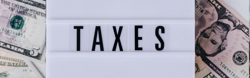 Steuerkonzept mit US-Dollar-Scheinen und Schriftzug „TAXES“ – Symbol für Tax Filing Thailand.