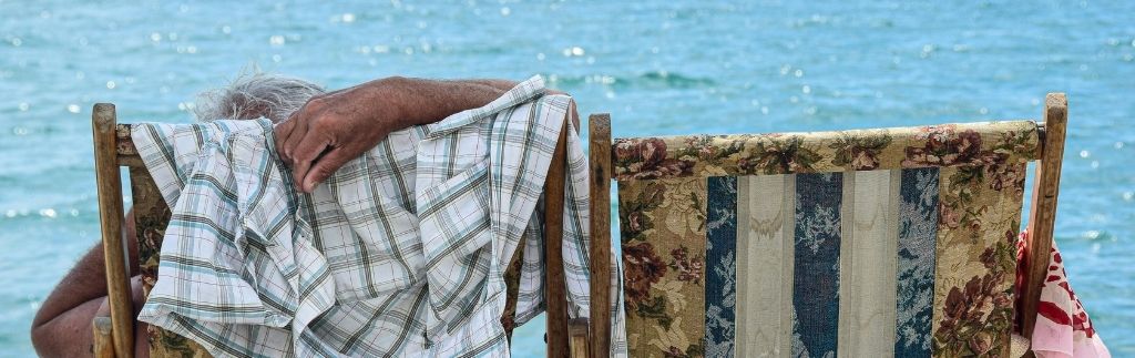 Älteres Paar genießt den Ruhestand Thailand am Meer, entspannt auf Holzstühlen mit Blick auf das blaue Wasser.