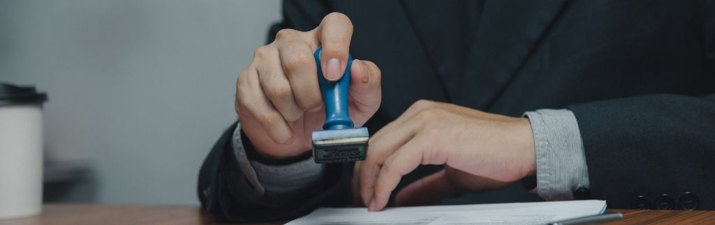 Geschäftsmann stempelt ein offizielles Dokument – Symbol für Genehmigungen und rechtliche Verfahren im Zusammenhang mit dem Destination Thailand Visum.