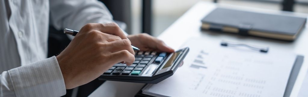 Person berechnet Finanzen mit Taschenrechner, Symbol für rechnungslegungsstandards thailand