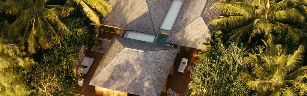 Luftaufnahme einer luxuriösen Immobilie in Thailand, umgeben von üppigem Grün und Palmen.