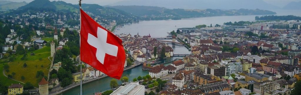 Vue de la Suisse avec drapeau national illustrant les démarches de visa pour Suisse en Thaïlande
