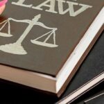 Книги по праву и символ справедливости на столе, иллюстрирующие юридические аспекты, включая запрет на продажу алкоголя в Таиланде.