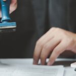 Visumantrag in Thailand: Ein Mann stempelt offizielle Dokumente für den Visumantrag.