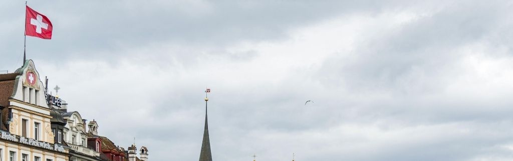 Vue sur un bâtiment en Suisse avec un drapeau suisse flottant, symbolisant la retraite en Thaïlande pour un Suisse.
