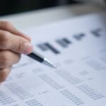 Un professionista esamina documenti finanziari, simbolizzando la gestione e l'analisi dei dati per un business in Thailandia.