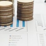 Graphiques financiers avec des pièces de monnaie, un stylo et des graphiques, représentant les considérations économiques pour créer une entreprise à Koh Samui.