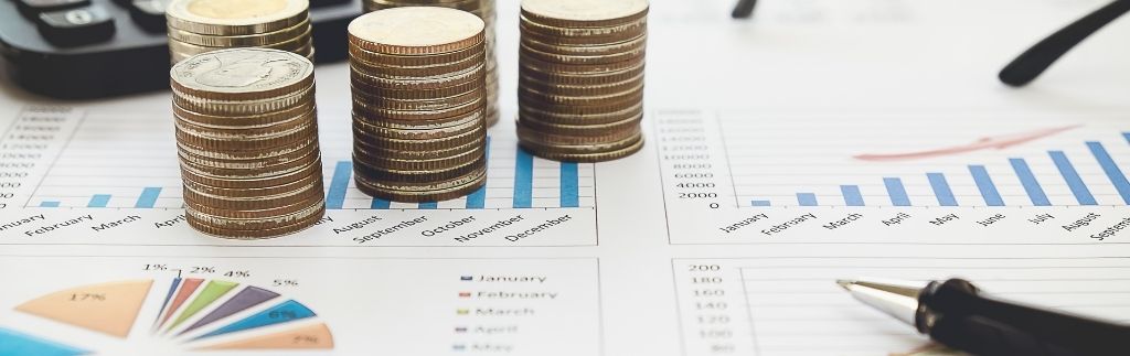 Graphiques financiers avec des pièces de monnaie, un stylo et des graphiques, représentant les considérations économiques pour créer une entreprise à Koh Samui.