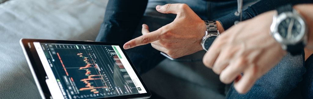 Zwei Unternehmer analysieren Finanzdaten auf einem Tablet während einer Beratung über Unternehmen in Thailand.