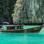 Retirement in Phuket with traditional boats in turquoise waters and limestone cliffs