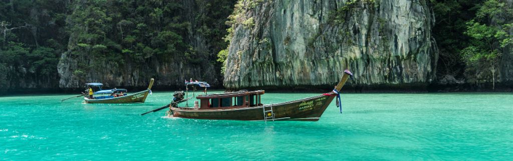 Retirement in Phuket with traditional boats in turquoise waters and limestone cliffs